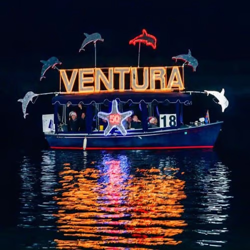 A boat displaying Ventura lettering and illuminated dolphins at a previous holiday parade